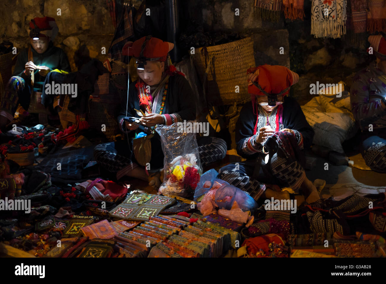 Red Dao Frauen machen und verkaufen Stammes-Kunsthandwerk auf einem Nachtmarkt in Sapa, Provinz Lao Cai, Vietnam Stockfoto