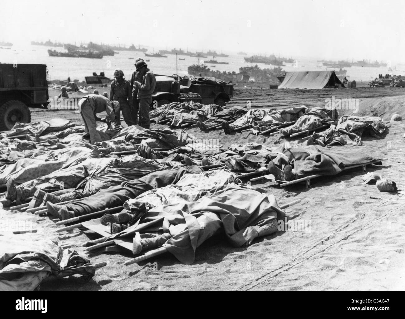 Toten Marines der 3. Marineabteilung, bedeckt mit ihren Ponchos, liegen am Strand nach der Schlacht von Iwo Jima. Stockfoto