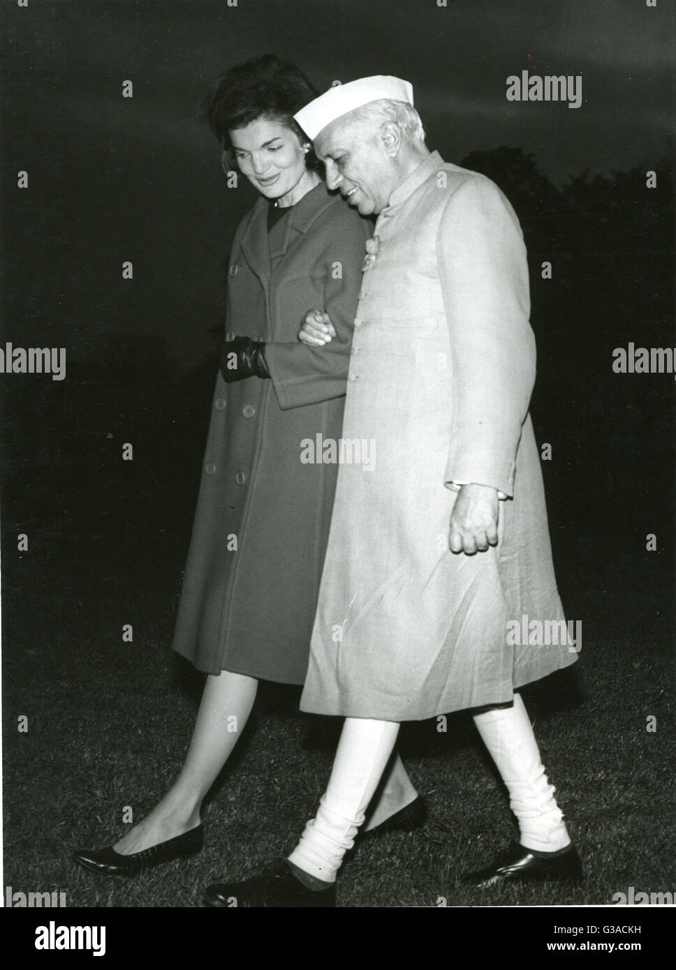 Frau Jacqueline Kennedy, Frau des Präsidenten Kennedy, geht Arm in Arm mit Premierminister Jawaharwal Nehru in Indien, da sie einen Hubschrauber zu verlassen und den Rasen des weißen Hauses überqueren. Stockfoto