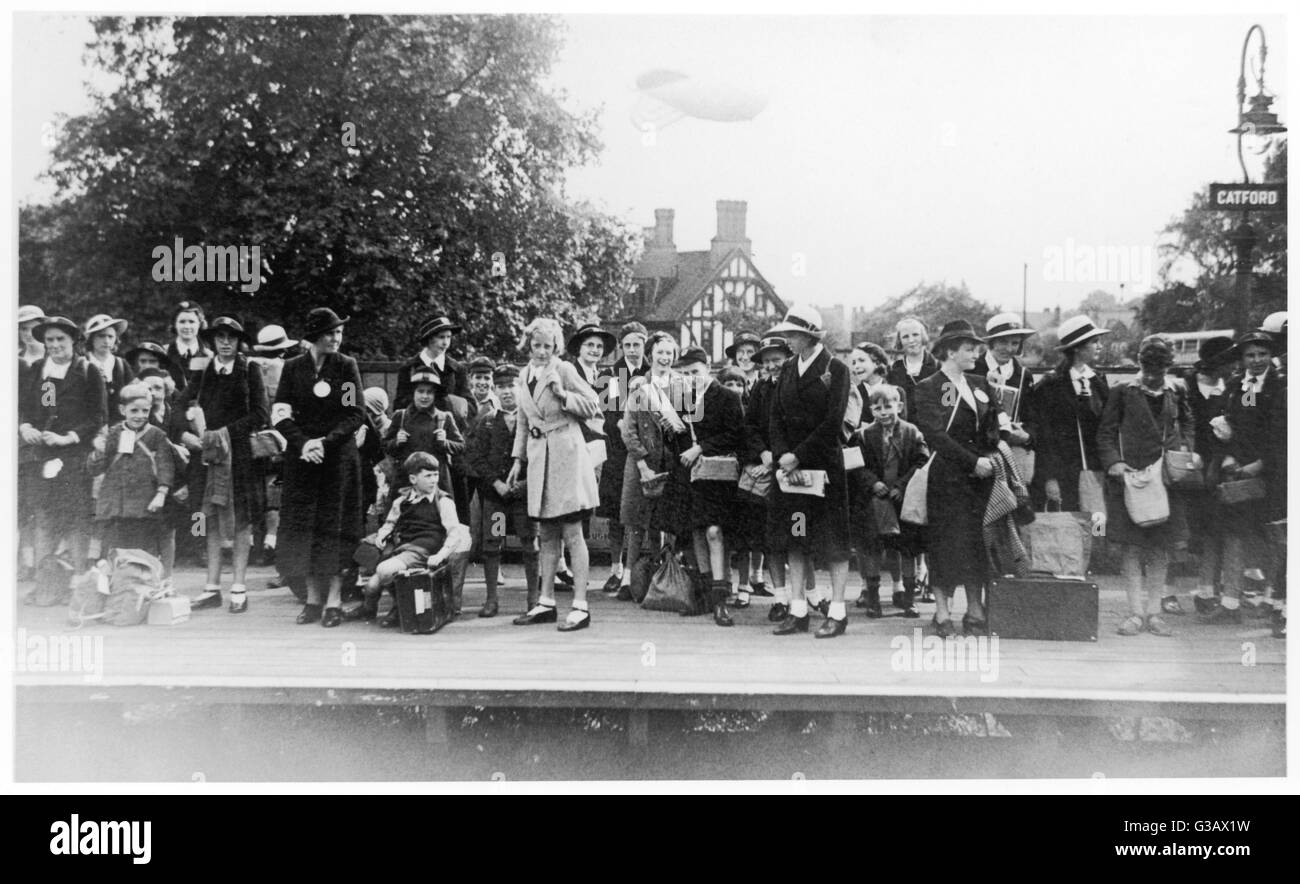 Eine Gruppe von Schülern begeistert komödienhaften warten mit ihren Schwestern auf der Plattform des nstige Bahnhof in Süd-Ost-London. (Beachten Sie die Flut Ballon hinter ihnen).     Datum: 1940 Stockfoto