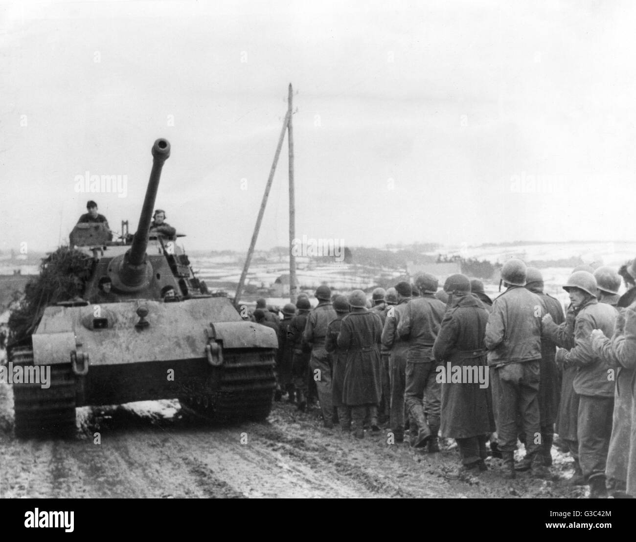 Belgische Straße in den Ardennen, ein deutscher Panzer Fortschritte, während amerikanische Kriegsgefangene nach hinten, während die deutsche Gegenoffensive marschiert sind, das als die Schlacht der Ausbuchtung Datum bekannt wurde: Dezember 1944 Stockfoto