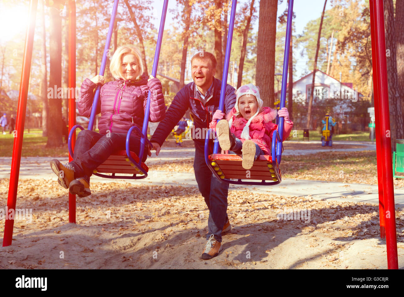 Junge fröhliche Familie Spaß auf Kinder Wippe im Park Stockfoto