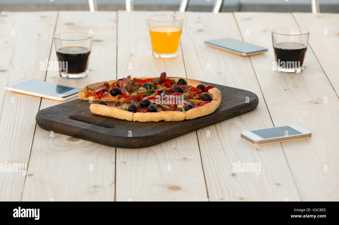 Frische Pizza Getränke und elektronischen Gadgets auf Holztisch Stockfoto