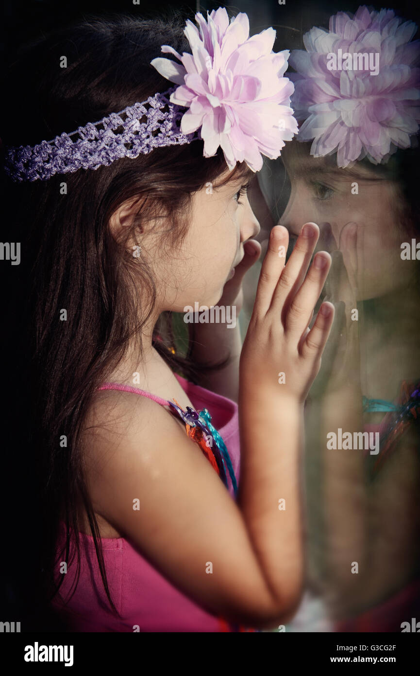 Kleines Mädchen Blick durch Fenster Stockfoto