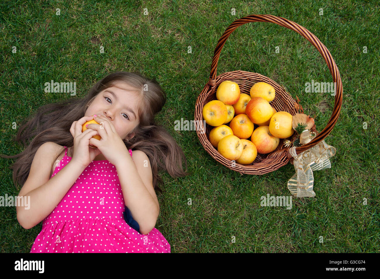 Kleines Mädchen auf Gras- und Essen Apfel liegen Stockfoto