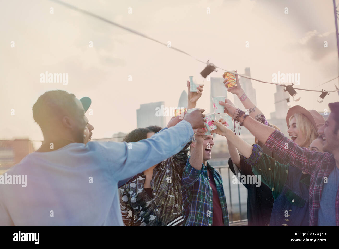 Begeisterte junge Erwachsene Freunde Toasten Cocktails auf Party auf dem Dach Stockfoto