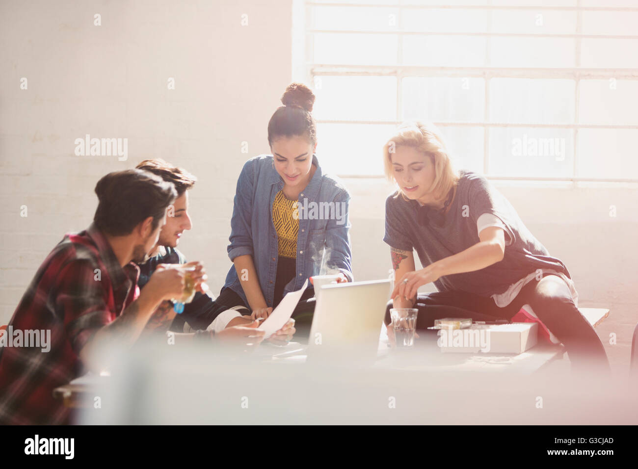 Kreative junge Geschäftsleute brainstorming am Laptop im sonnigen Büro Stockfoto