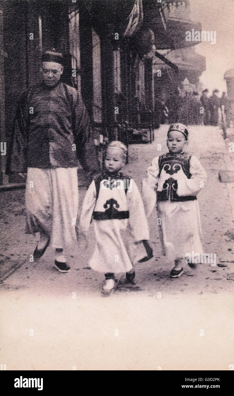 Zwei chinesische Kinder in traditioneller Kleidung zu Fuß durch die Stadt  mit ihrem Vater. Datum: ca. 1910er Jahre Stockfotografie - Alamy