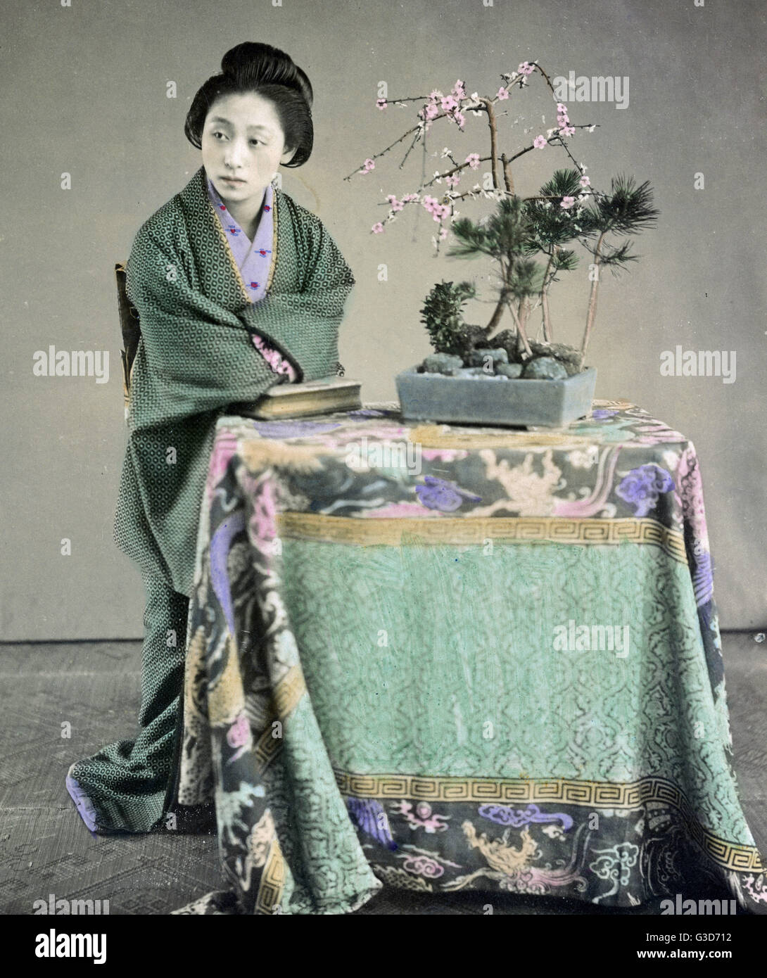 Wolman saß an einem Tisch mit einem bonzai-Baum, Japan um 188 Stockfoto