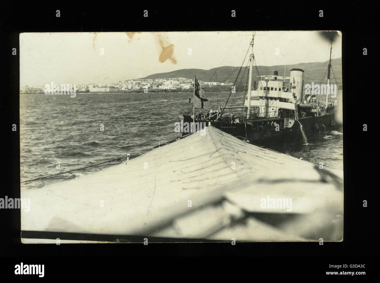 RFA (Royal Fleet Auxiliary) Prestol Belgol-Klasse Tanker und Kriegsschiff mit Küste (möglicherweise Spanien) im Hintergrund.      Datum: ca. 1920er Jahre Stockfoto