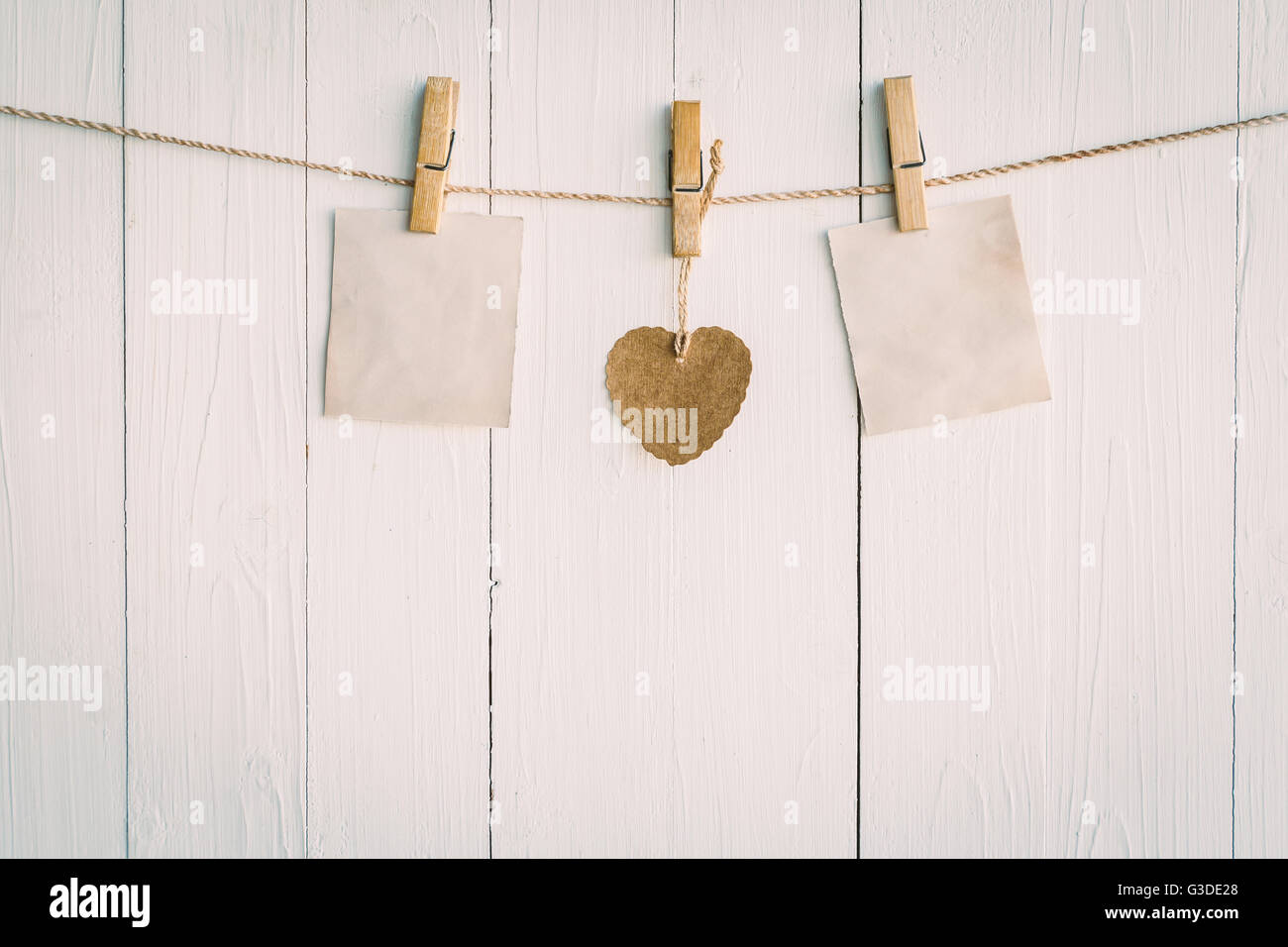 Zwei leere Altpapier und braunen Herzen hängen. Auf weißem Holz Hintergrund mit Vintage-Stil. Stockfoto