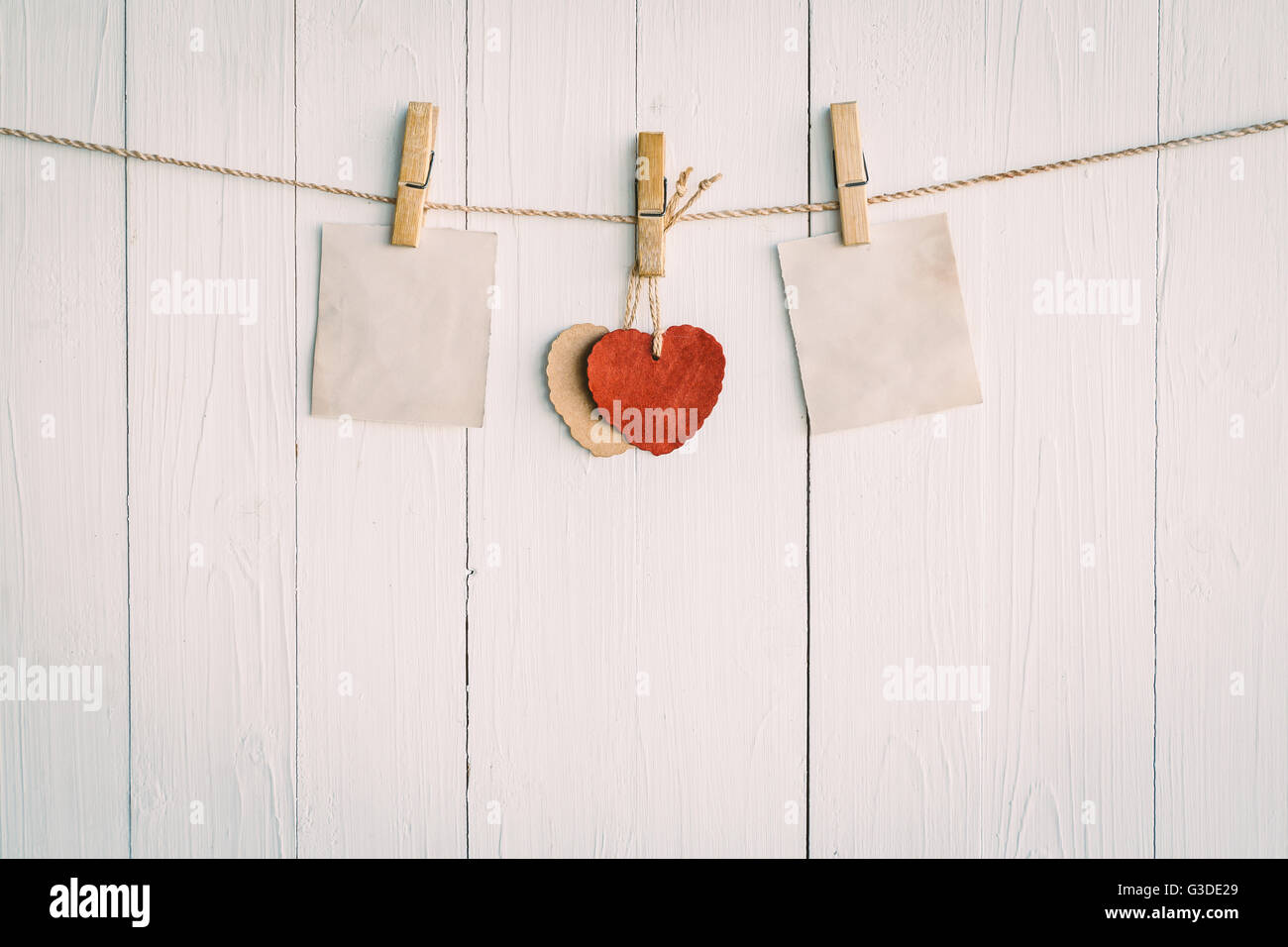 Zwei leere Altpapier und roten Herzen hängen. Auf weißem Holz Hintergrund mit Vintage-Stil. Stockfoto