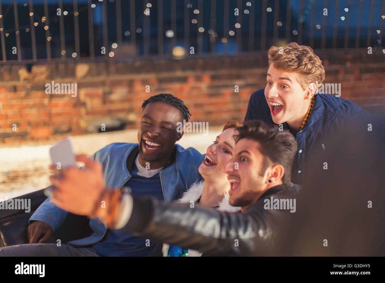 Begeisterte junge Erwachsene, die die Selfie bei Nacht auf dem Dach-party Stockfoto