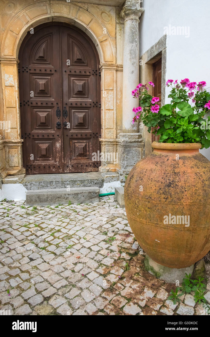 Gepflasterten Innenhof mit reich verzierten Tür und große Terrakotta-Topf, Obidos, Estremadura, Portugal Stockfoto