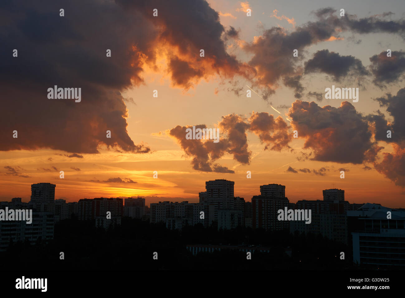 Sonnenuntergang in der Stadt mit dunklen Silhouetten der Gebäude unten Stockfoto
