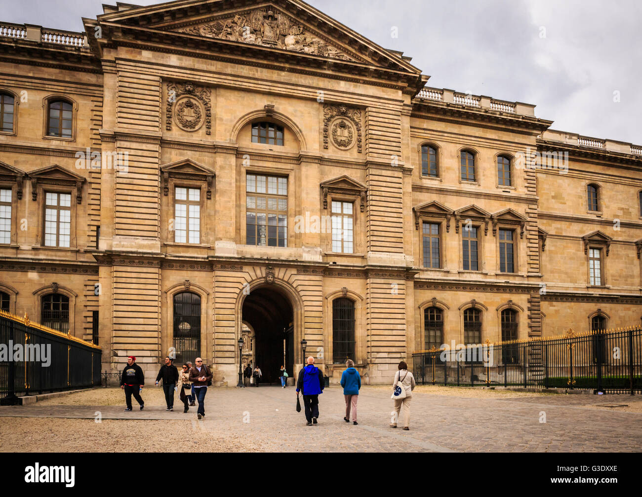 Touristen flanieren vor dem Louvre, einst ein königlicher Palast und jetzt ein Museum in Paris und eine wichtige touristische Attraktion. Stockfoto