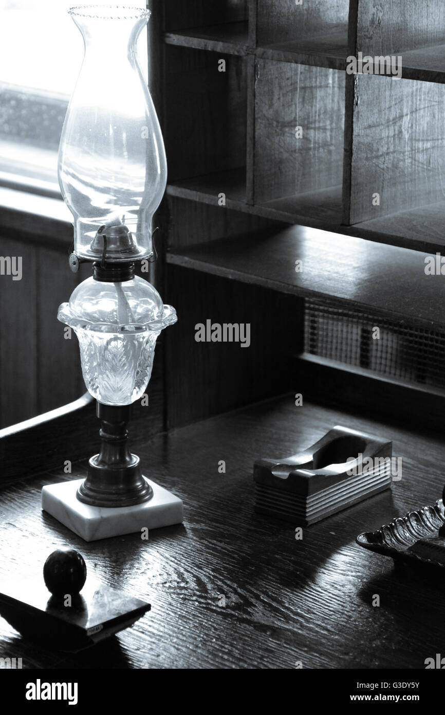 Eine alte Schreibset einschließlich Tinte gut und Löschblatt zusammen mit Petroleumlampe sitzen auf alten Schreibtisch aus Holz mit Taube Loch Schrank Stockfoto