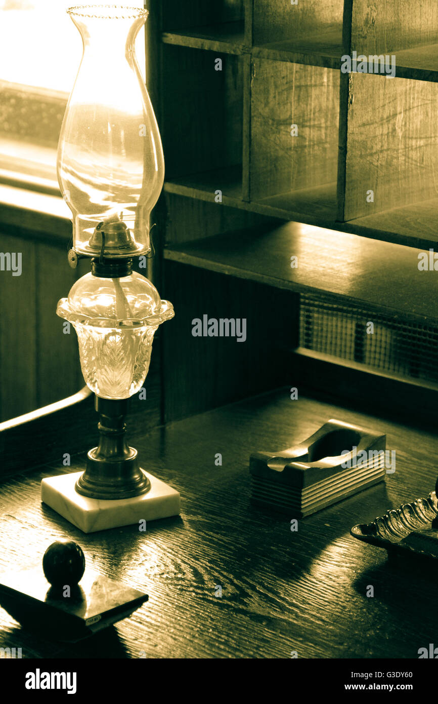Eine alte Schreibset einschließlich Tinte gut und Löschblatt zusammen mit Petroleumlampe sitzen auf alten Schreibtisch aus Holz mit Taube Loch Schrank Stockfoto
