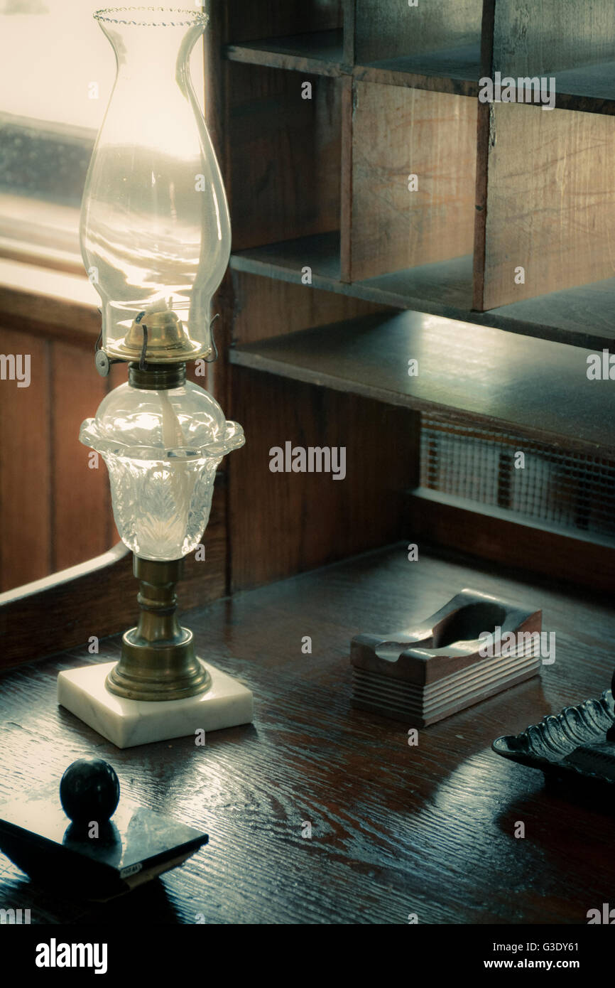 Eine alte Schreibset einschließlich Tinte gut und Löschblatt zusammen mit Petroleumlampe sitzen auf alten Schreibtisch aus Holz mit Taube Loch Schrank Stockfoto