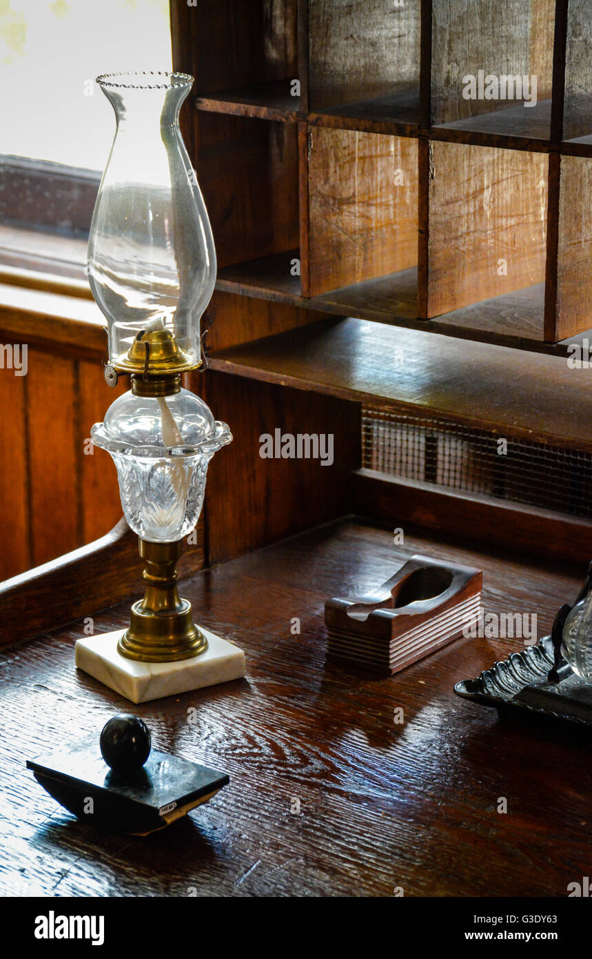 Eine alte Schreibset einschließlich Tinte gut und Löschblatt zusammen mit Petroleumlampe sitzen auf alten Schreibtisch aus Holz mit Taube Loch Schrank Stockfoto