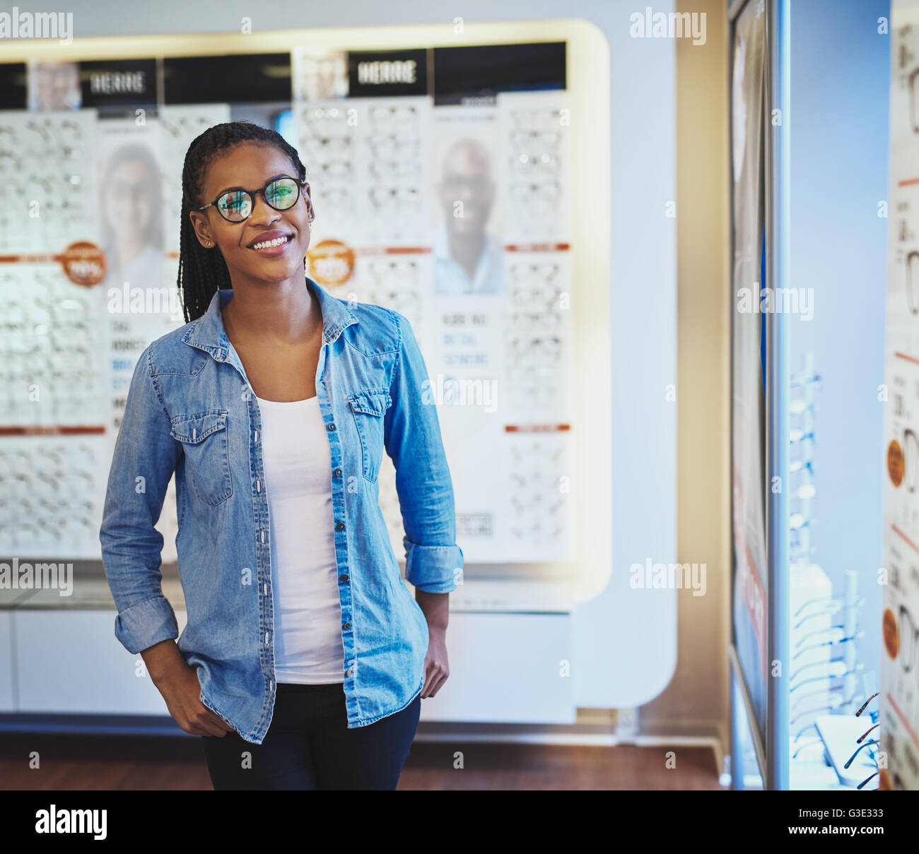 Single lächelnd schöne schwarze Frau in Brillen mit beiden Händen in den Taschen, während vor der Anzeige an eye Wear Shop Stockfoto