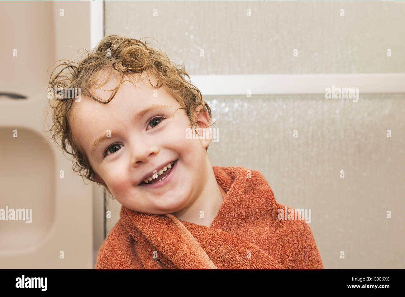 Junge, Lächeln und immer nach dem Duschen im Badezimmer mit einem Handtuch trocken; St. Albert, Alberta, Kanada Stockfoto