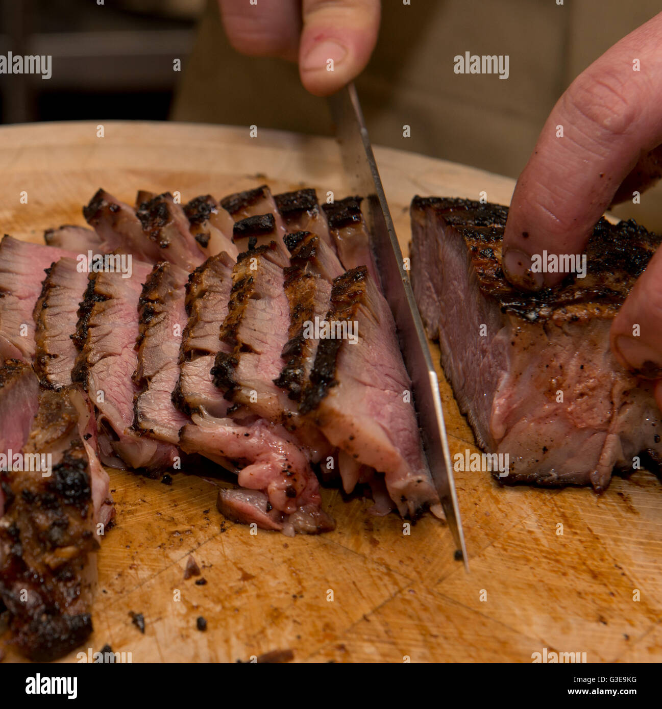 Ribeye-Steak vom Grill in einem Holz befeuerten Ofen geschnitten wird. Stockfoto