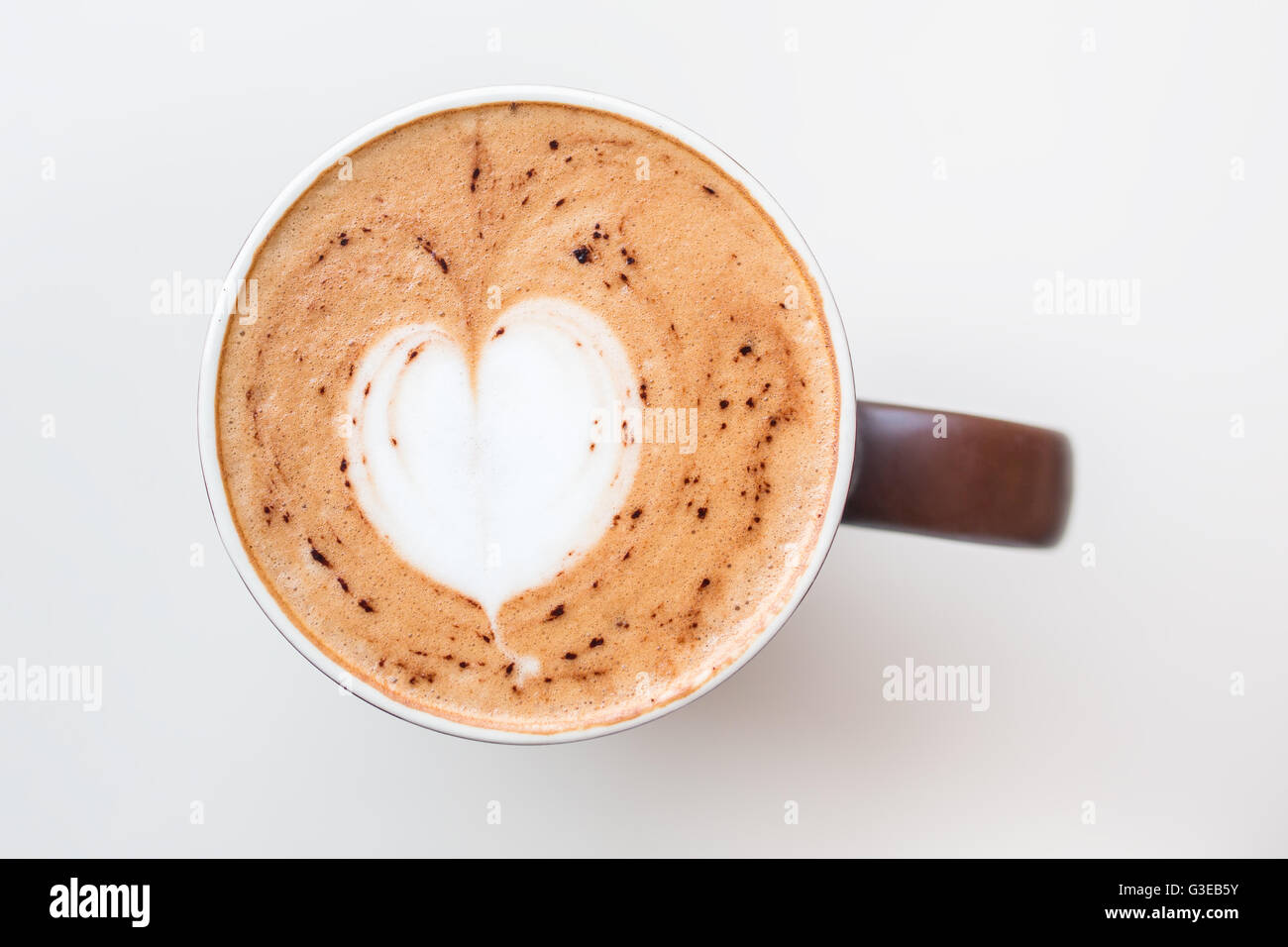 Cappuccino Tasse mit dem milchigen Schaum an der Spitze in Form eines Herzens in einer braunen Tasse auf weißen Tisch von oben gesehen Stockfoto