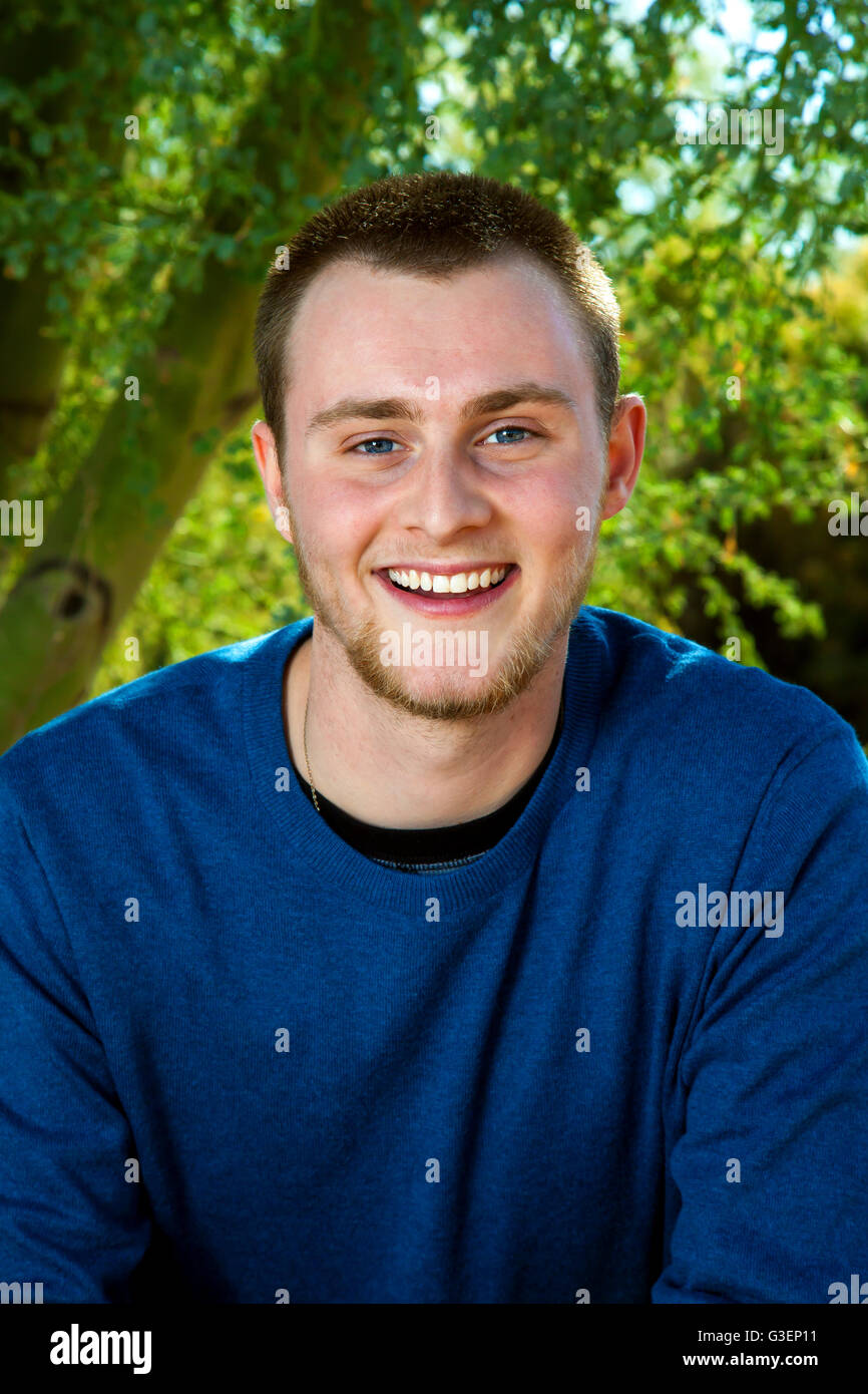 Outdoor-Porträt eines jungen Mannes in ein Hemd mit langen Ärmeln, blau.  Er hat blaue Augen, kurze Haare und einen leichten Bart. Stockfoto