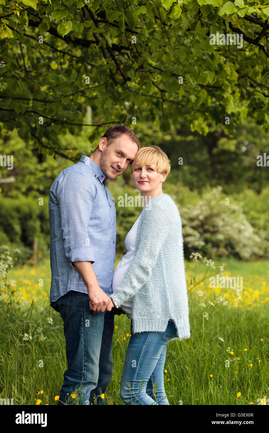 Glückliches Paar im Park, schwangere Frau und ihr Mann Stockfoto