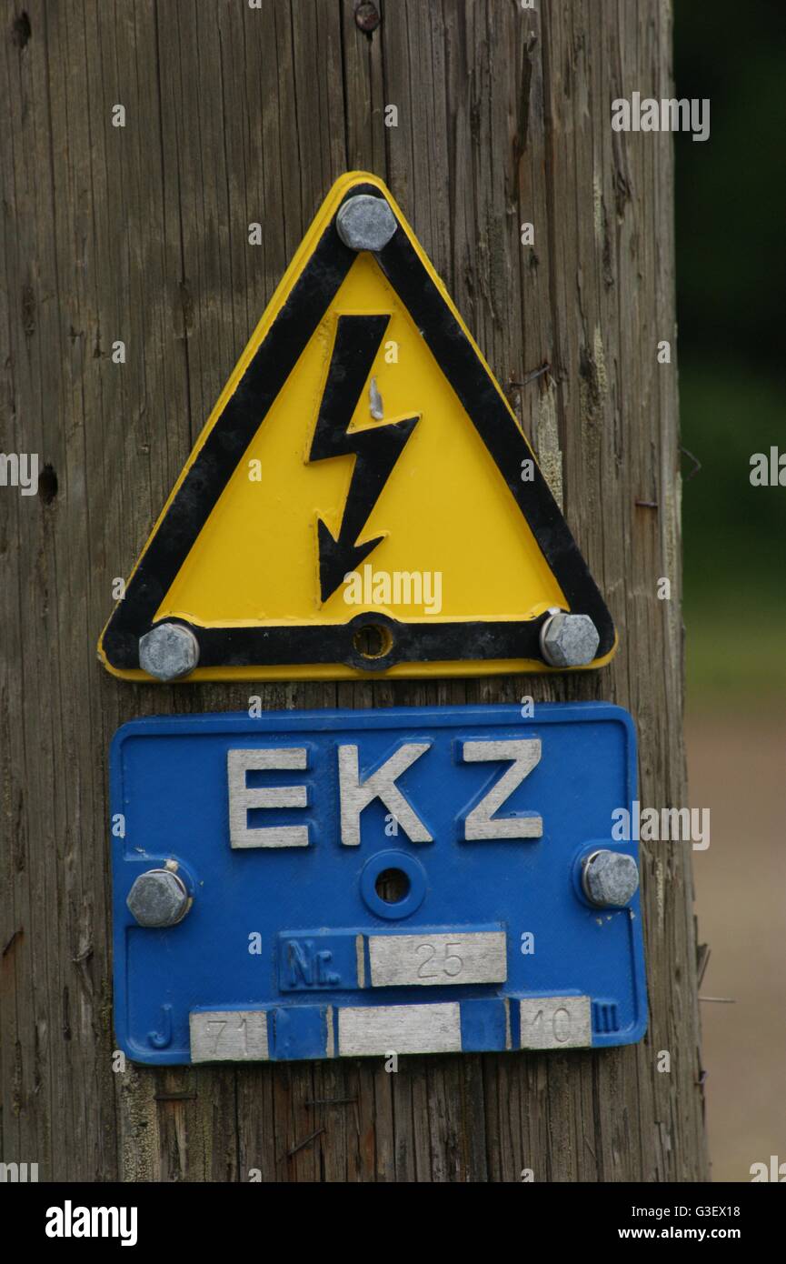 dreieckige Warnschild am Strom Pylon, schwarzer Blitz auf gelbem Hintergrund, EKZ Stockfoto