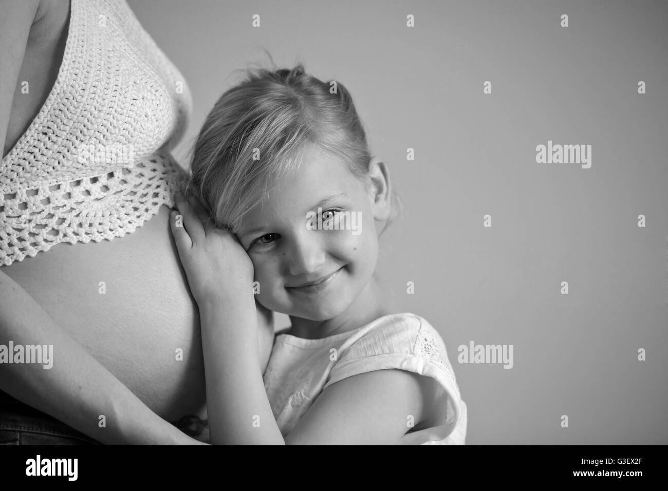 Junges Mädchen hält den Bauch der schwangeren Mutter Stockfoto