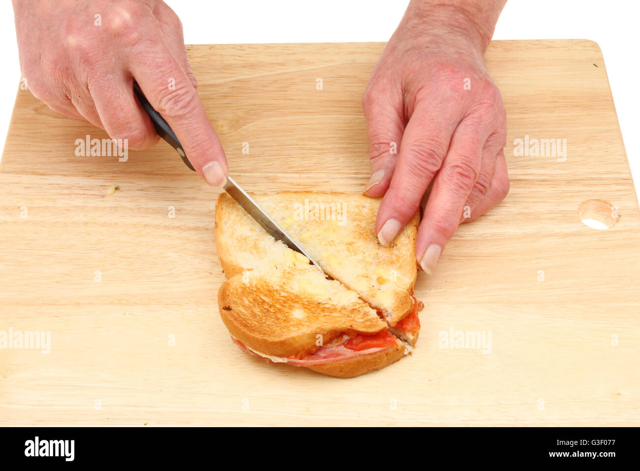 Nahaufnahme von ein paar Hände schneiden einen Toast auf ein Schneidbrett aus Holz Stockfoto