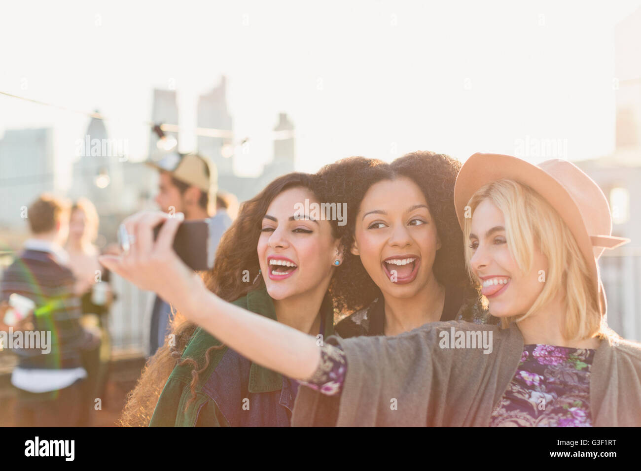 Begeisterte junge Frauen, die die Selfie auf Party auf dem Dach Stockfoto