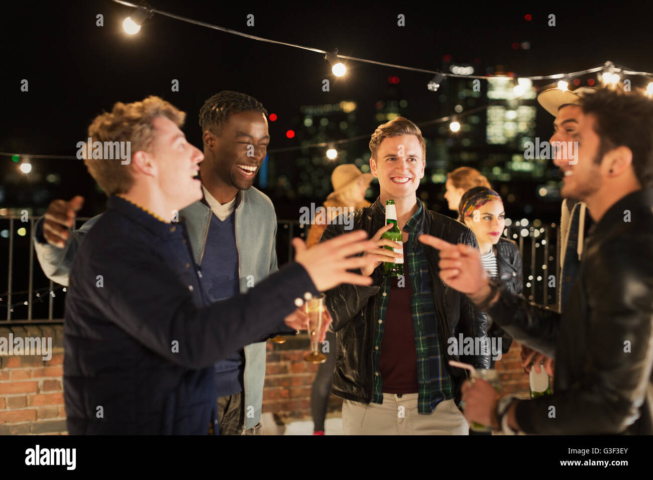 Junge Männer tranken und lachten auf Party auf dem Dach Stockfoto