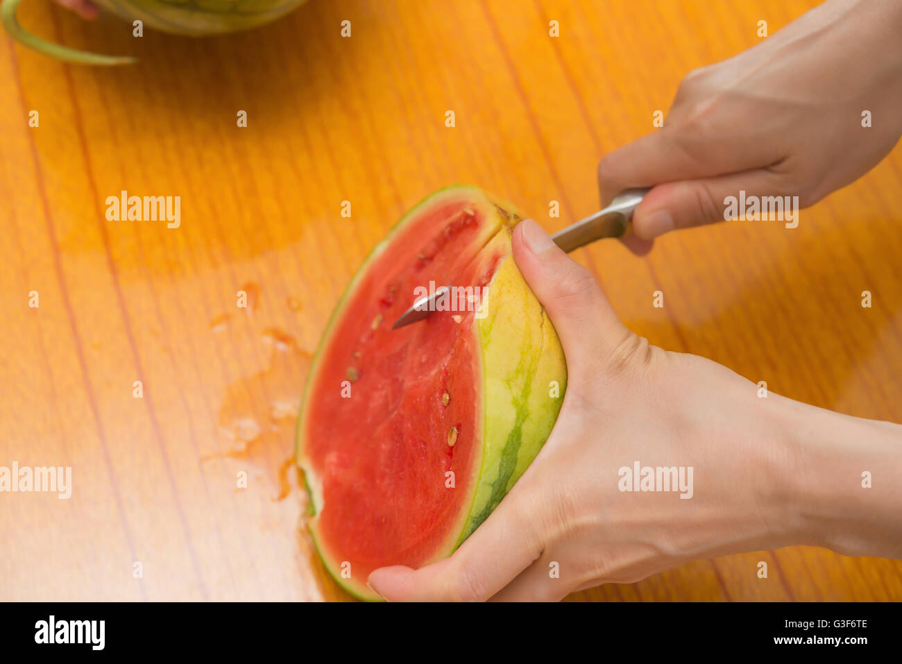 Schneiden eine Wassermelone mit Messer auf einem Tisch Stockfoto