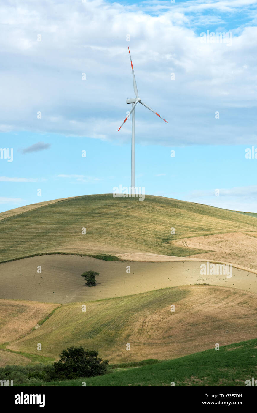 Einzelne Windturbine in Ackerland auf einem Hügel mit wogenden Feldern und Wiesen eine Quelle von Strom aus erneuerbaren Energiequellen Stockfoto