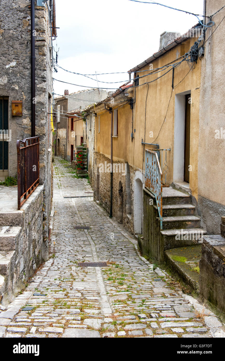 Alte schmale gepflasterte Straße führt zwischen Wohnhäusern in einer italienischen Stadt an einem grauen Himmel-Tag Stockfoto