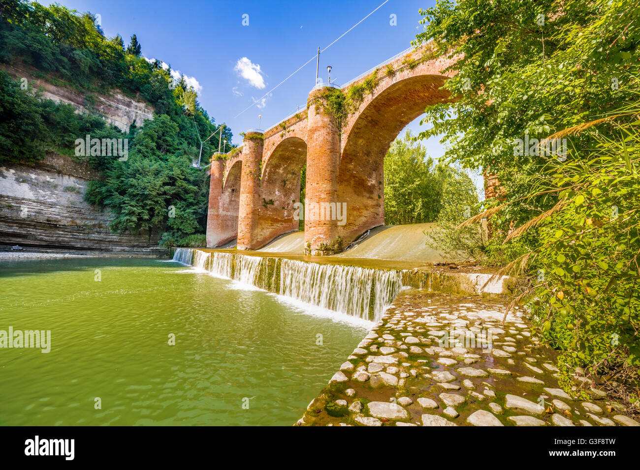 Frischen Wasser des Flusses unter vierzehnten Jahrhundert Brücke im Mauerwerk in einem kleinen Dorf in den Hügeln in Romagna, Italien Stockfoto