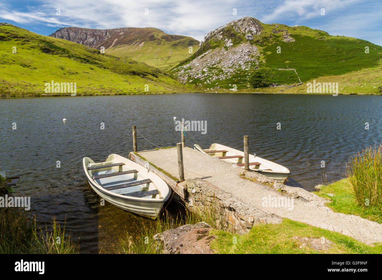 Zwei Boote vertäut Steg an kleinen See. Llyn y Dywarchen Reservoir, Rhyd Ddu, Gwynedd, Wales, Vereinigtes Königreich Stockfoto