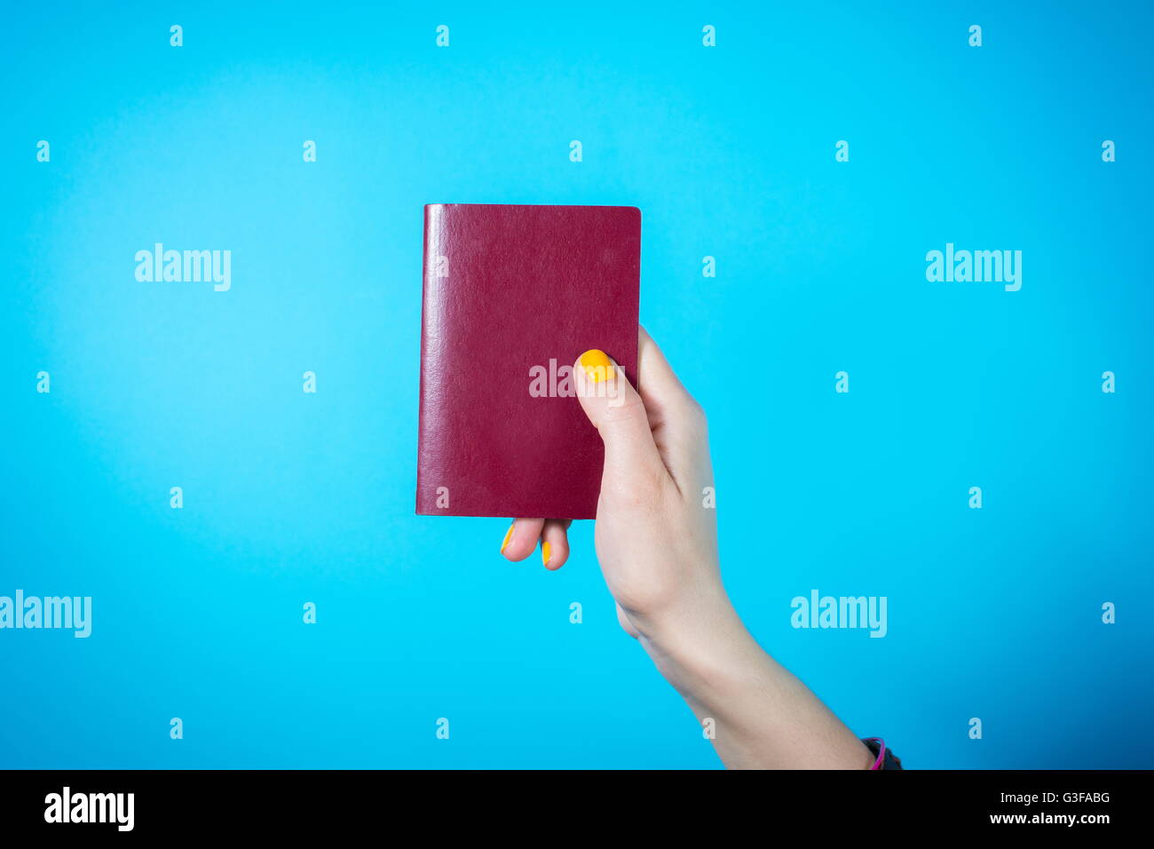 Zarte Frauenhand im Besitz einer roten Pass vor blauem Hintergrund Stockfoto
