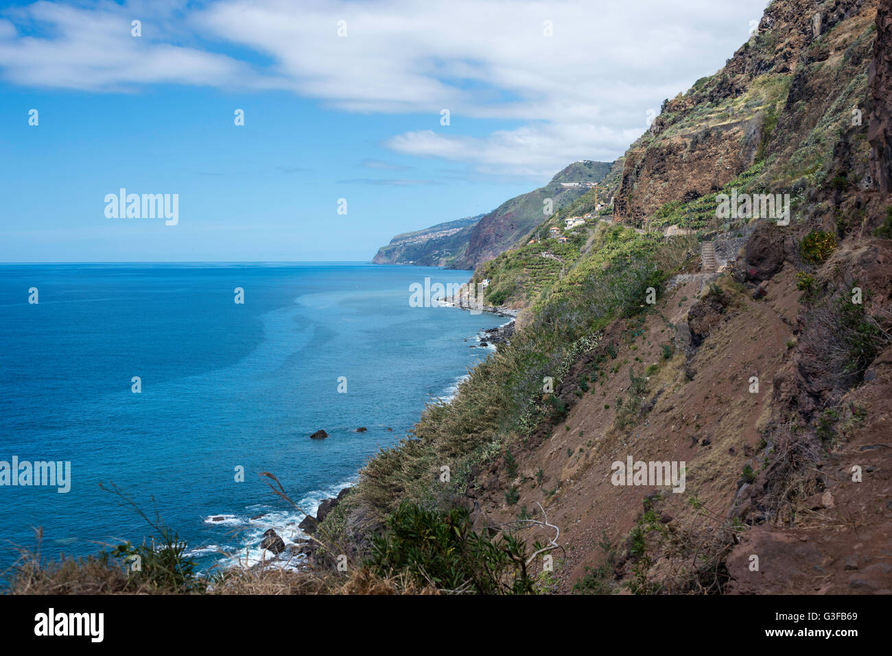 die vulkanischen Gesteinen des East Caost von Madeira mit blauen Himmel und grüne Vegetation in der Nähe von Calheta Dorf Stockfoto