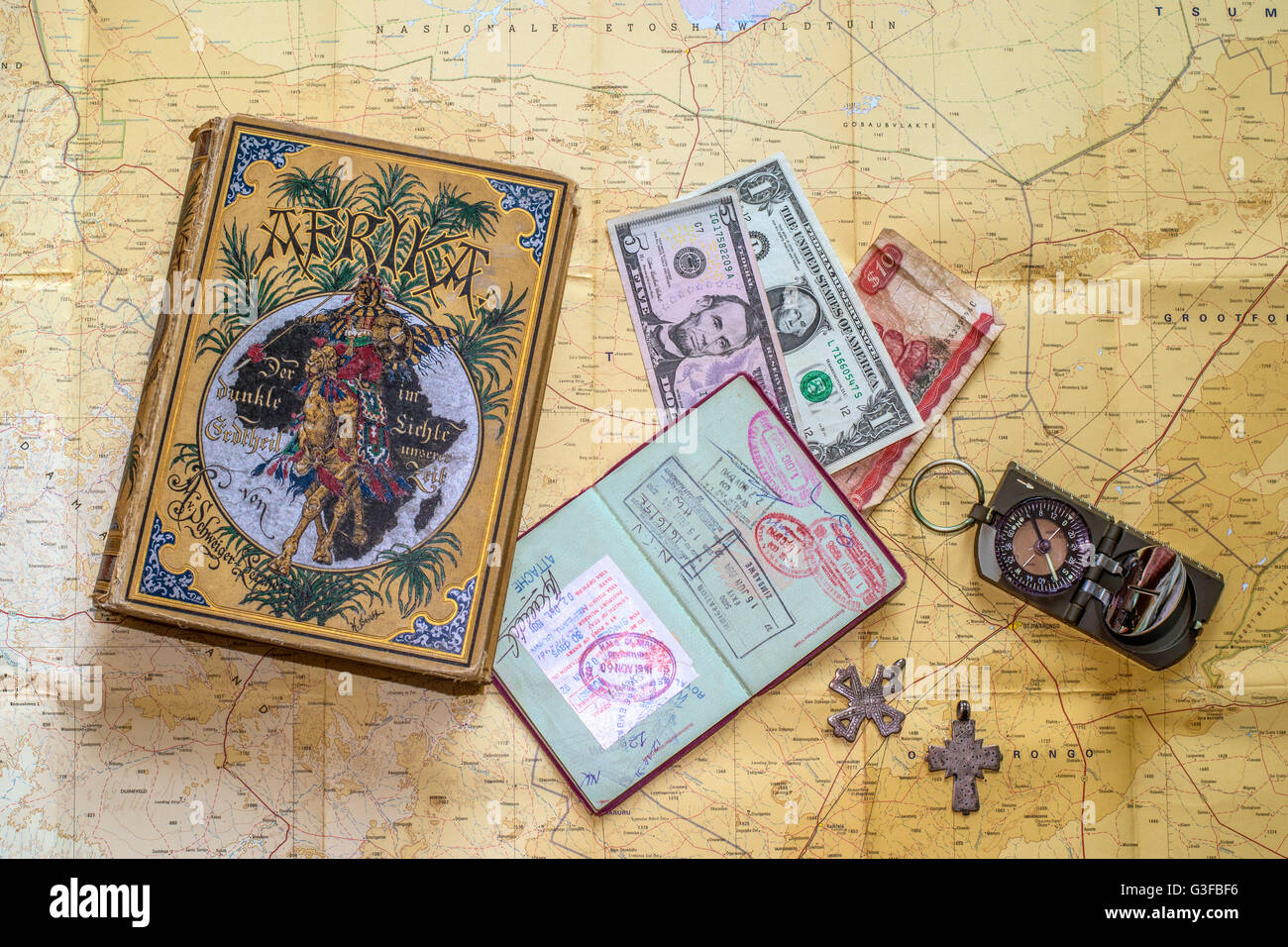 Stillleben mit Erinnerungen, Buch aus dem Jahr 1889, Kompass, Pass, zwei alte äthiopische Kreuze und Geld angeordnet auf einer Karte von Namibia Stockfoto