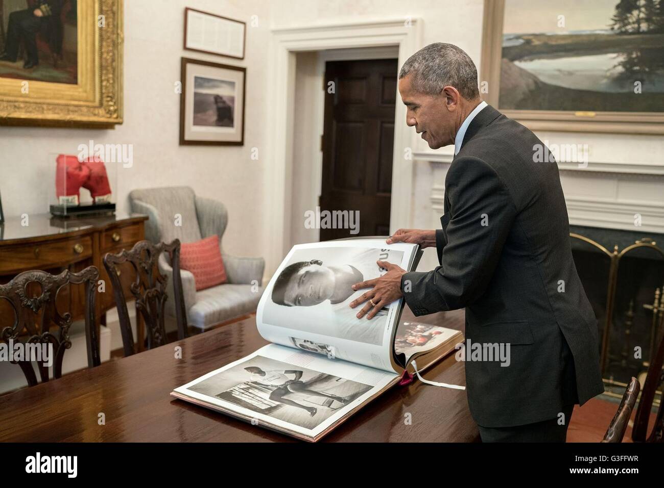 US-Präsident Barack Obama sieht auf Fotos von Muhammad Ali während einer Aufzeichnung auf Reflexionen von Muhammad Ali für Facebook Live im Oval Office Private Dining Room 9. Juni 2016 in Washington, DC. Obama konnte nicht an der Beerdigung teilzunehmen, da seine Tochter Malia ihren High-School-Abschluss zur gleichen Zeit hatte. Stockfoto