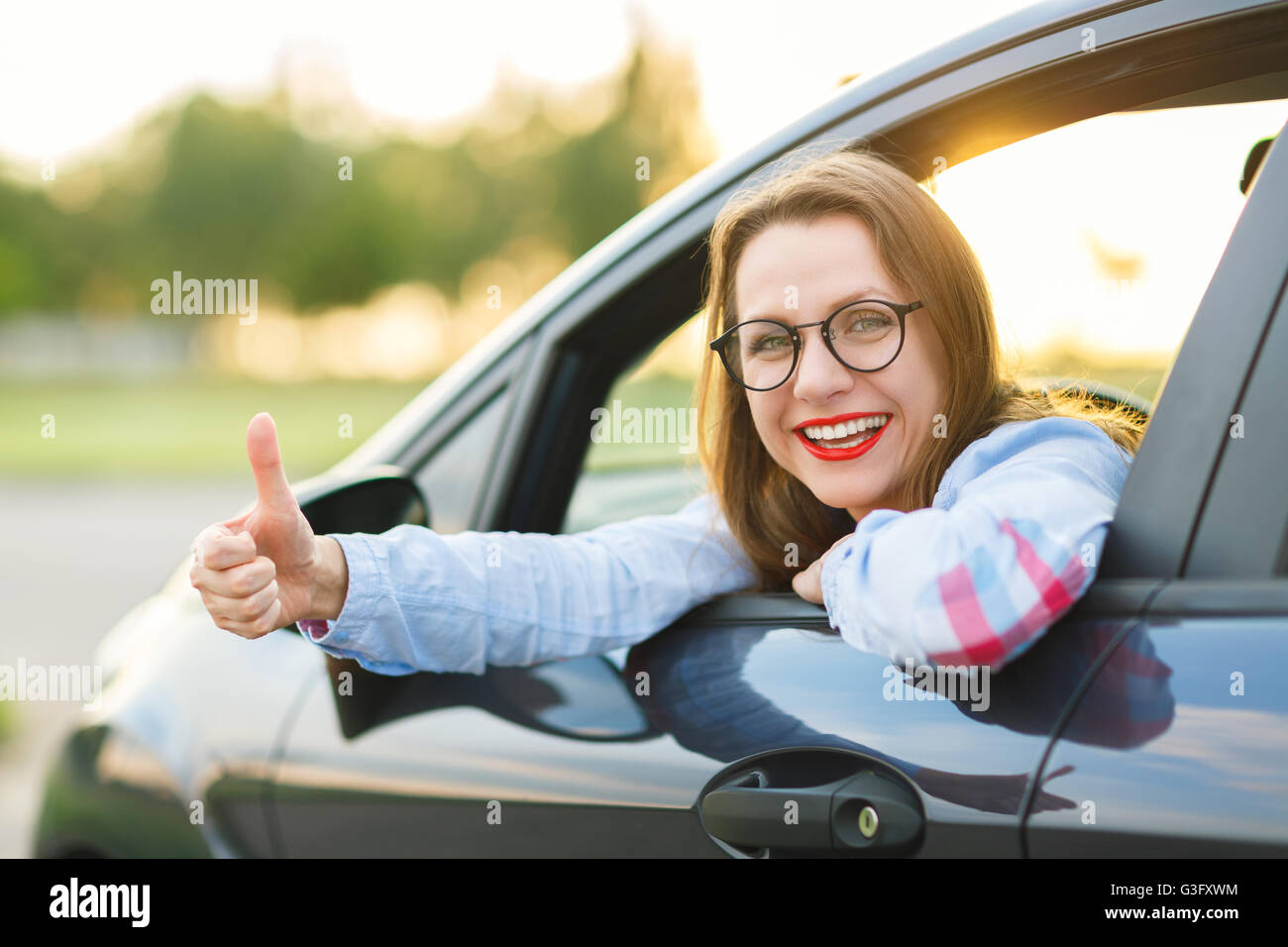 Glückliche Mädchen sitzen in einem Auto mit Daumen - Konzept für den Kauf eines Gebrauchtwagens oder einen Mietwagen Stockfoto