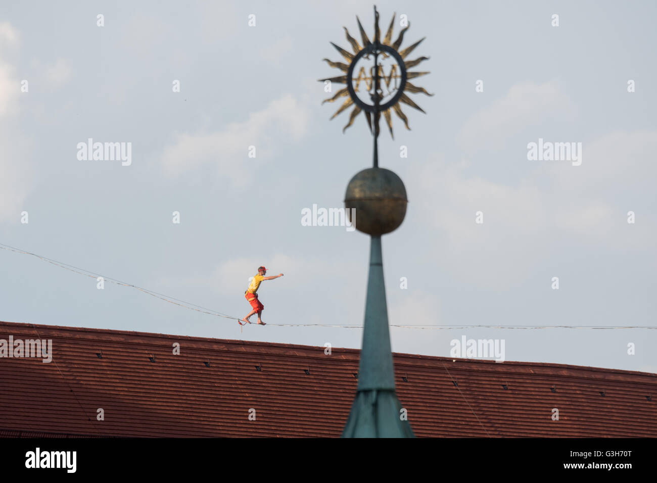 Straubing, Deutschland. 24. Juni 2016. Lukas Irmler zu Fuß entlang einer Slackline über die alte Stadt von Straubing, Deutschland, 24. Juni 2016. Eine 169 Meter langen Slackline wurde zwischen dem Turm der Basilika St. Jakob und dem Stadtturm als Teil der Feier zum 700. Jahrestag der Stadtturm überspannt. Foto: ARMIN WEIGEL/Dpa/Alamy Live-Nachrichten Stockfoto