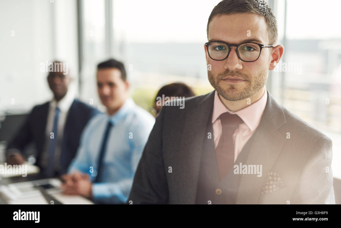 Ernsthafte junge Unternehmer in einer Sitzung mit Multirassischen Kollegen ständigen aufmerksam in die Kamera schaut mit Sun flare über h Stockfoto