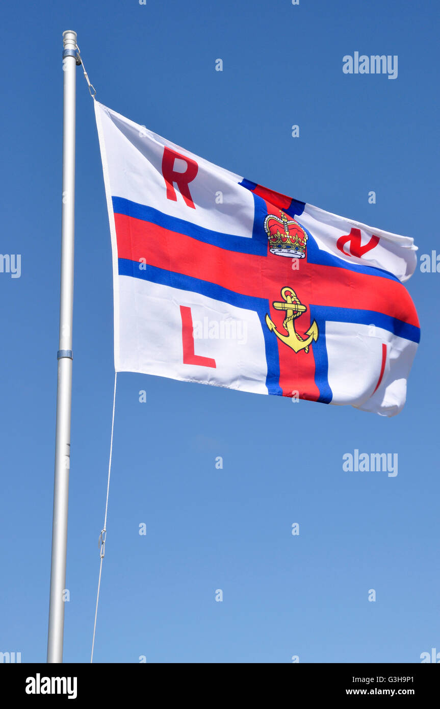 Polzeath Klippe Top Strandwache - Flagge der RNLI - fliegen im Wind - gegen strahlend blauen Himmel Cornwall Stockfoto