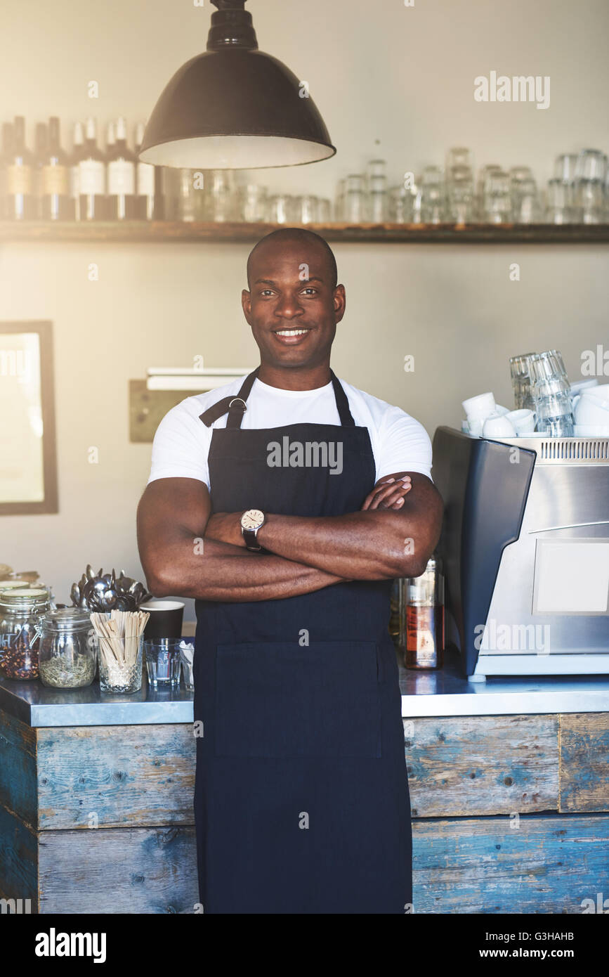 Gut aussehend Unternehmer steht Café Zähler gesäumt von Gläsern und einer rostfreien Stahl Kaffeemaschine Stockfoto