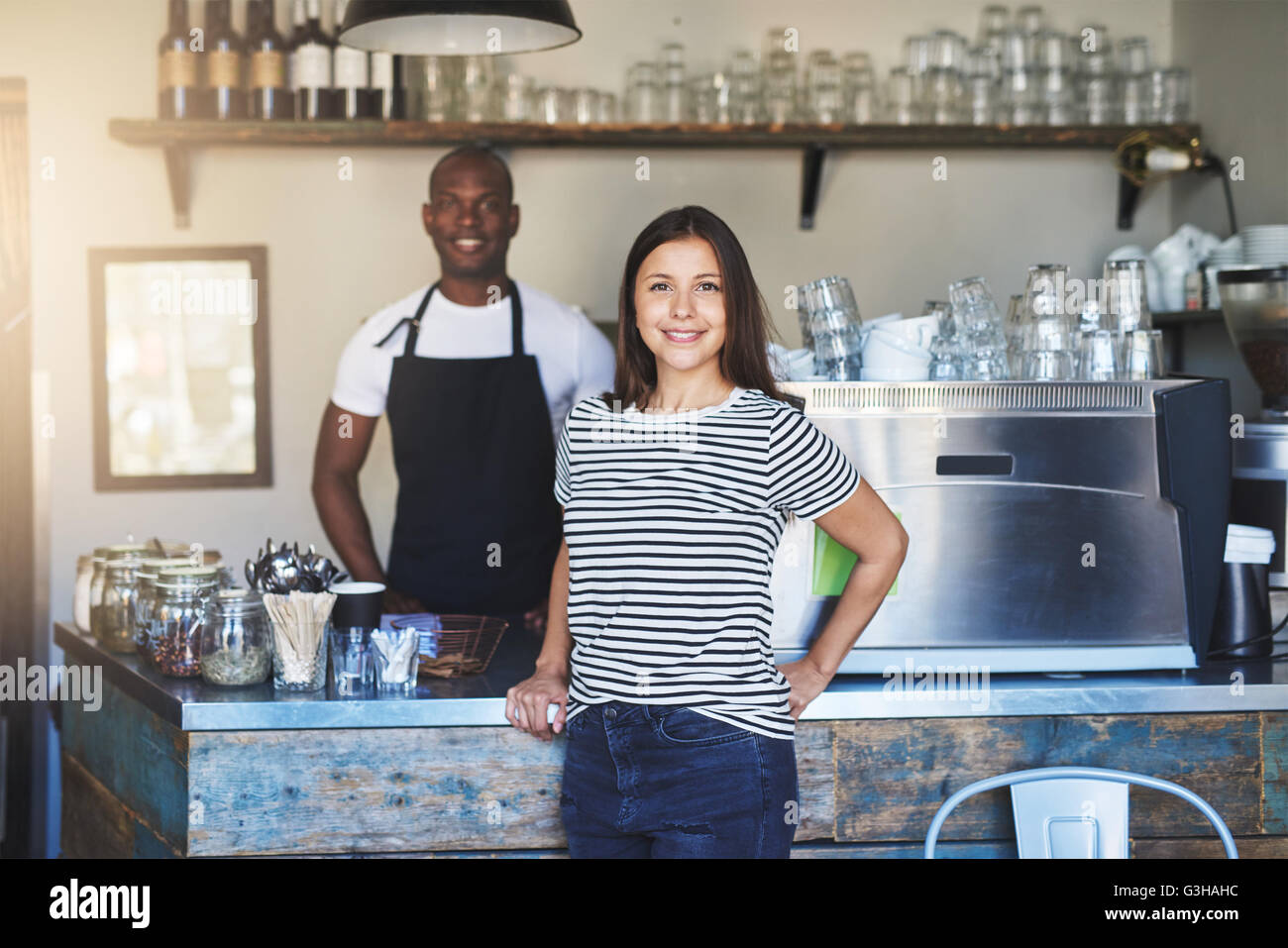 Paar des Lächelns männliche und weibliche Food-Service Arbeitnehmer stehen in der Nähe von Verkaufstheke im Kaffeehaus mit leichten Flare in Ecke Stockfoto